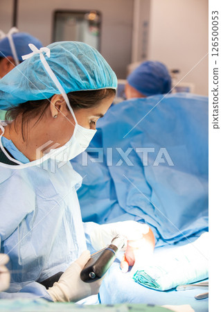 Female doctor performing a surgery. Orthopedic surgeon. Surgery and insurance concept. Hand surgery. Traumatology and orthopedics concept. Female doctor performing a surgery. Orthopedic surgeon. Surgery and insurance concept. Hand surgery. Traumatology and orthopedics concept. 126500053