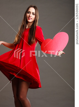 Woman in red dress holds heart sign 126500091