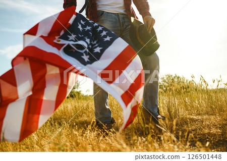 4th of July. American Flag. Traveler with the flag of America. The man in a hat, a backpack, a shirt and jeans. 126501448