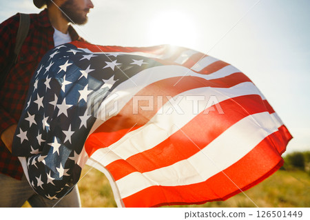 4th of July. American Flag. Traveler with the flag of America. The man in a hat, a backpack, a shirt and jeans. 4th of July. American Flag. Traveler with the flag of America. The man in a hat, a backpack, a shirt and jeans. 126501449