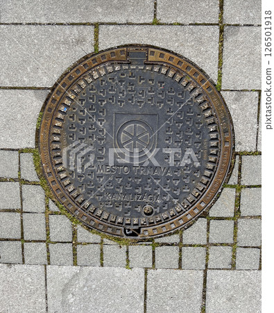 Trnava, Slovakia - 17.04.2025: Paving stones with a metal canal manhole. Stone pavement as a background texture. Road surface made of stone blocks. Trnava, Slovakia - 17.04.2025: Paving stones with a metal canal manhole. Stone pavement as a background texture. Road surface made of stone blocks. 126501918