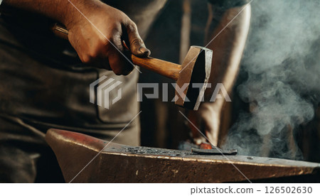 The moment a blacksmith strikes metal / Documentary-style material that conveys traditional techniques and strength 126502630