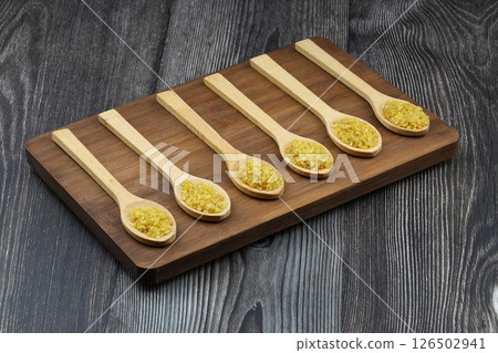 Dry bulgur wheat grains with a spoon close up Dry bulgur wheat grains with a spoon close up 126502941