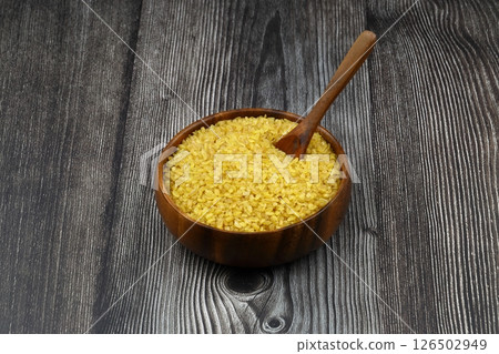 Dry bulgur wheat grains with a spoon close up Dry bulgur wheat grains with a spoon close up 126502949