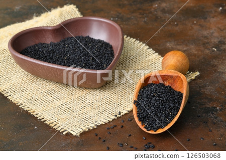 Black cumin seeds and essential oil with bowl and wooden shovel or spoon. Nigella Sativa 126503068