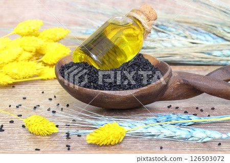 Black cumin seeds and essential oil with bowl and wooden shovel or spoon. Nigella Sativa Black cumin seeds and essential oil with bowl and wooden shovel or spoon. Nigella Sativa 126503072
