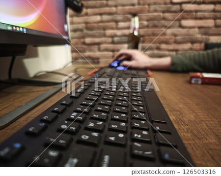Black keyboard resting on wooden desk near computer mouse, programmer working intently at home office workspace 126503316