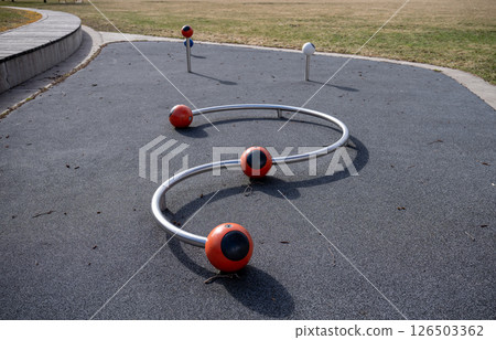 Unique playground structure with metal curves and colored spheres on rubber surface 126503362