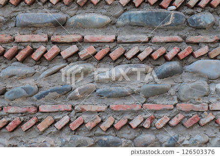 Intricate wall design features alternating stone and brick patterns 126503376