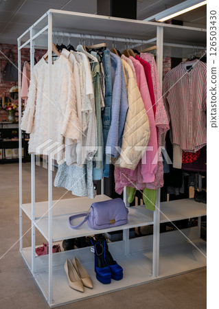 women's summer clothing in various colors and fabrics hanging on hangers in thrift shop. Second hand women's summer clothing in various colors and fabrics hanging on hangers in thrift shop. Second hand 126503430