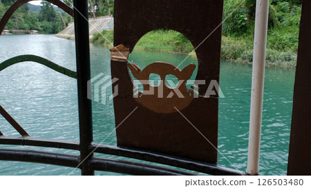 Boat on calm river with tropical views and a wooden tarsier carving adds charm to the deck  126503480