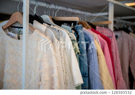women's summer clothing in various colors and fabrics hanging on hangers in thrift shop. Second hand 126503532