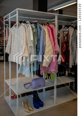 women's summer clothing in various colors and fabrics hanging on hangers in thrift shop. Second hand women's summer clothing in various colors and fabrics hanging on hangers in thrift shop. Second hand 126503539