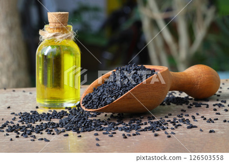 Black cumin seeds and essential oil with bowl and wooden shovel or spoon. Nigella Sativa Black cumin seeds and essential oil with bowl and wooden shovel or spoon. Nigella Sativa 126503558