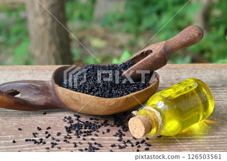 Black cumin seeds and essential oil with bowl and wooden shovel or spoon. Nigella Sativa Black cumin seeds and essential oil with bowl and wooden shovel or spoon. Nigella Sativa 126503561