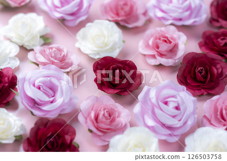 Colorful artificial roses arranged on a pink background 126503758