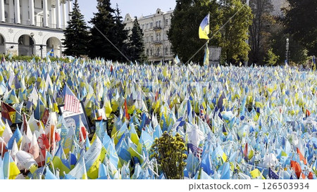 Many small blue-yellow flags with names of the dead war against russia. Memorial of the fallen soldiers, children, women in the capital of Ukraine. Concept of tragedy and misfortune. Close up 126503934