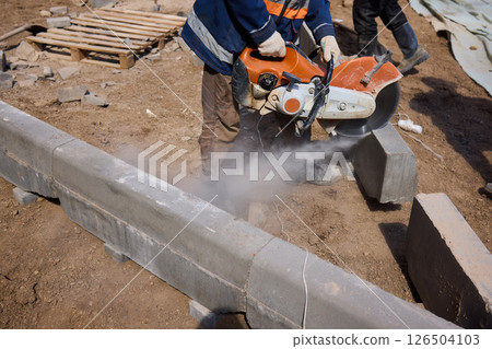 A hardworking construction worker skillfully cutting concrete using a powerful saw tool 126504103