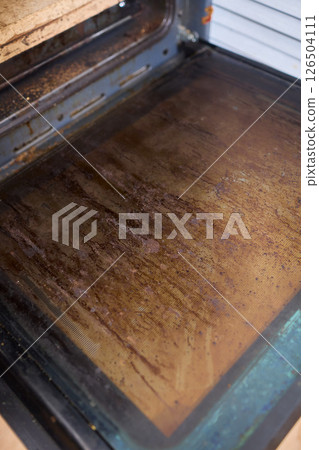 Interior of a dirty oven displaying baked on grease and unsightly stains throughout it Interior of a dirty oven displaying baked on grease and unsightly stains throughout it 126504111