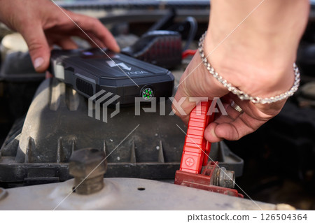 Closeup photo of black car battery connected with jumper cables for repair or recharging 126504364