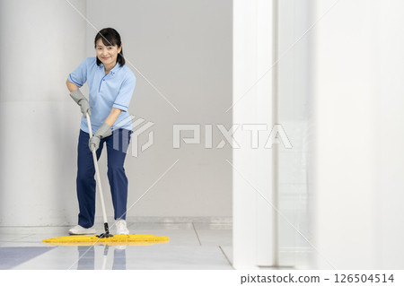 大樓清潔圖片:一名 50 多歲的女清潔人員正在拖地,看著鏡頭 大樓清潔圖片:一名 50 多歲的女清潔人員正在拖地,看著鏡頭 126504514