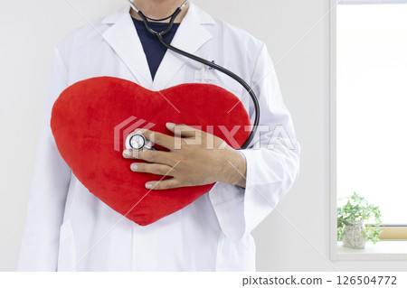 Image of a doctor putting a stethoscope to a heart-shaped cushion (Japanese, male, no face, 30s) Image of a doctor putting a stethoscope to a heart-shaped cushion (Japanese, male, no face, 30s) 126504772