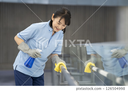 大樓清潔圖：一名 50 多歲的女性清潔人員正在擦拭走廊的扶手 126504998