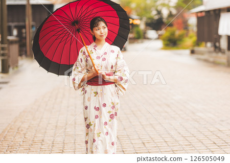 秋季中旬，一位身穿浴衣的年輕女子在雨中穿過溫泉小鎮。 [拍攝合作：新發田市電影委員會] 126505049