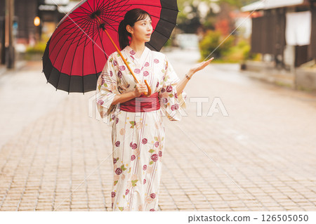 秋季中旬，一位身穿浴衣的年輕女子在雨中穿過溫泉小鎮。 [拍攝合作：新發田市電影委員會] 126505050