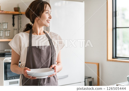 Young Asian woman in an apron doing housework in the kitchen 126505444