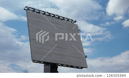 A large digital billboard looms over a war-torn area, emphasizing the contrast between modern technology and the impact of ongoing conflict on daily life 126505894