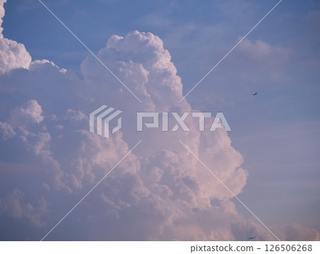A passenger plane flies into a cumulonimbus cloud rising in the summer sky 126506268