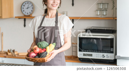Asian woman/housewife holding vegetables in kitchen 126506308