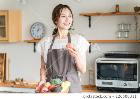 Asian woman holding vegetables in the kitchen, housewife 126506311