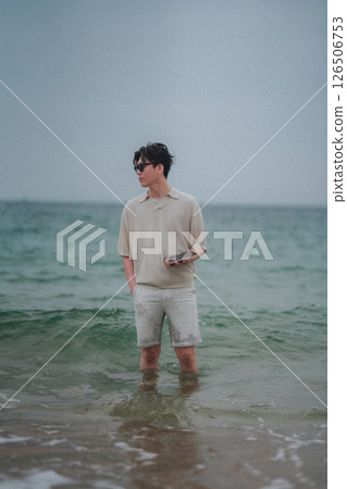 A man working on a tablet on the beach at a resort 126506753