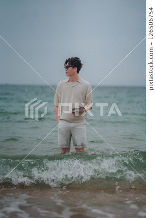 A man working on a tablet on the beach at a resort A man working on a tablet on the beach at a resort 126506754