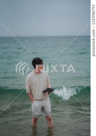 A man working on a tablet on the beach at a resort A man working on a tablet on the beach at a resort 126506755