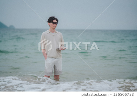 A man working on a tablet on the beach at a resort 126506758