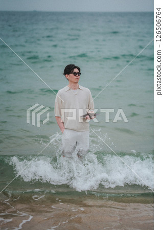 A man working on a tablet on the beach at a resort 126506764
