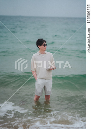 A man working on a tablet on the beach at a resort 126506765