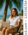 A Young Woman Enjoying Working on Her Laptop Relaxing at the Beautiful Beach Setting 126506784
