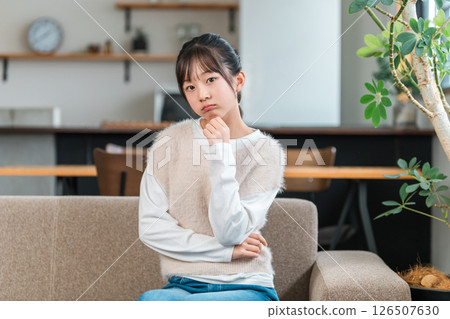 一位憂心忡忡的小學生或國中女生坐在客廳的沙發上思考著。 126507630