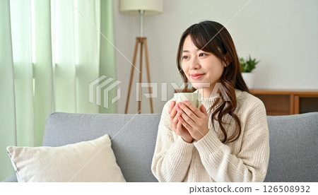 一位 30 多歲的微笑女士在斯堪的納維亞風格的客廳裡休息 126508932