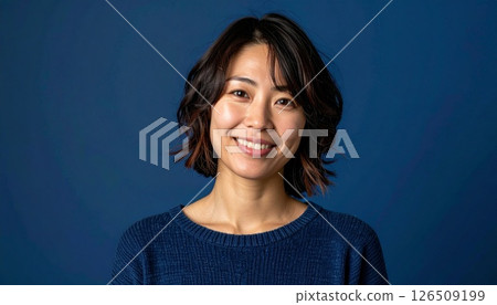 A woman with a medium layered cut stands out against a navy blue background 126509199