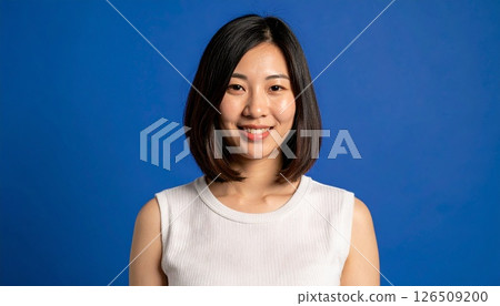 A woman with a medium layered cut stands out against a navy blue background 126509200