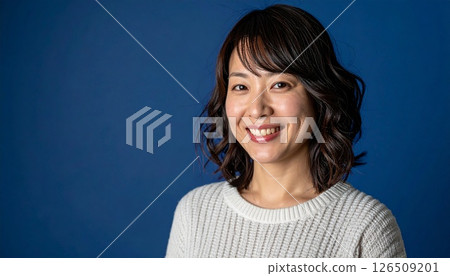 A woman with a medium layered cut stands out against a navy blue background 126509201