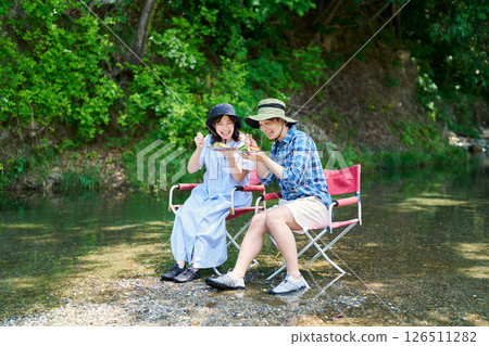 Men and women eating curry by the river 126511282