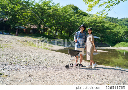 Men and women having a barbecue by the river 126511765
