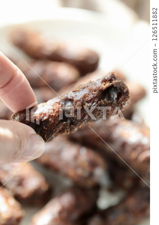 手指握著厚厚的雙層黑糖花林糖 手指握著厚厚的雙層黑糖花林糖 126511882