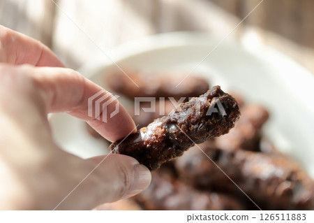 手指握著厚厚的雙層黑糖花林糖 手指握著厚厚的雙層黑糖花林糖 126511883